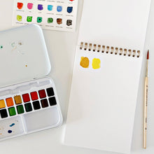 Load image into Gallery viewer, Spiral-bound watercolor paper pad with paint swatches, watercolor tin palette, and round brush