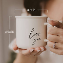 Load image into Gallery viewer, White ceramic coffee mug with 'love you' text held in hands, showing dimensions