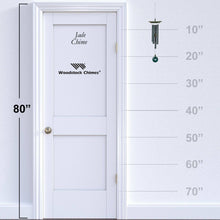 Load image into Gallery viewer, Woodstock Jade Chime wind chime with green stone accent shown against 80-inch door for size reference