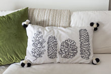 Load image into Gallery viewer, White lumbar pillow case with black embroidered pinecone designs and black and white pom-pom corners