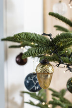 Load image into Gallery viewer, Gold acorn-shaped glass Christmas ornament hanging on a decorated evergreen tree