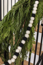 Load image into Gallery viewer, Black and white felt ball garland draped over evergreen cedar stair garland