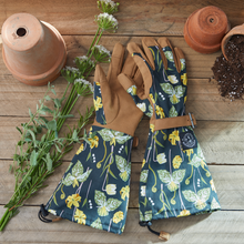 Load image into Gallery viewer, Floral patterned gardening gloves with extended arm protection displayed with terracotta pots and plants