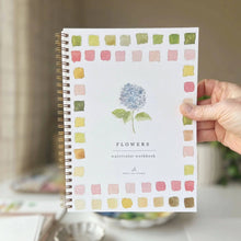 Load image into Gallery viewer, Spiral-bound watercolor workbook with flower painting and color swatches border held by hand