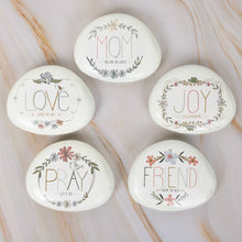 Load image into Gallery viewer, Five decorative white garden stones with inspirational words MOM, LOVE, JOY, PRAY, FRIEND surrounded by floral designs