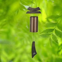 Load image into Gallery viewer, Bronze wind chime with wooden top and striker hanging among green foliage