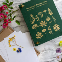 Load image into Gallery viewer, Green linen botanical flower press with gold foil plant designs next to pressed flowers