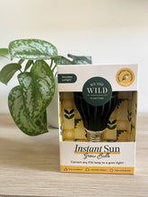 Load image into Gallery viewer, Live the Wild Instant Sun Grow Bulb in packaging next to potted houseplant