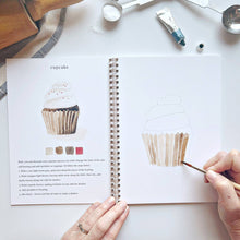 Load image into Gallery viewer, Hands painting watercolor cupcake in spiral-bound baking art instruction workbook with brushes and paints