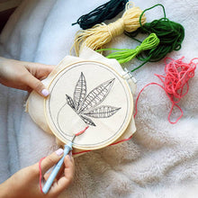 Load image into Gallery viewer, Hands holding embroidery hoop with botanical leaf design and colorful yarn skeins