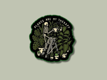 Load image into Gallery viewer, Black circular sticker with skeleton watering plants and text 'Plants Are My Therapy'