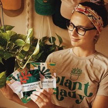Load image into Gallery viewer, Person holding colorful instant plant food fertilizer packets with tropical leaf design packaging