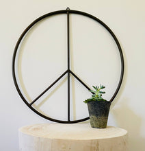 Load image into Gallery viewer, Black metal peace sign wall art displayed on white wooden table with small succulent plant
