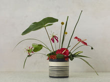 Load image into Gallery viewer, Striped black and white ceramic Sinclair Pot displayed with tropical floral arrangement