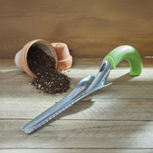 Load image into Gallery viewer, Ergonomic hand weeder tool with green grip handle and metal blade on wooden surface with spilled soil