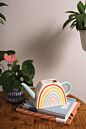 Load image into Gallery viewer, White ceramic watering can with colorful rainbow design on wooden surface with plants