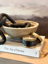 Load image into Gallery viewer, Gold tin candle with eucalyptus spritz scent on wooden surface next to decorative bowl and book