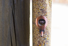 Load image into Gallery viewer, Copper finish bird seed feeder with spout dispensing mixed birdseed into container