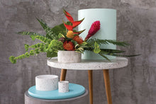 Load image into Gallery viewer, White speckled terrazzo planters displayed on modern furniture with tropical plants and colorful flowers