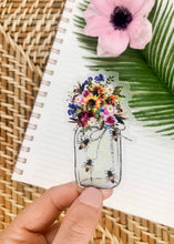 Load image into Gallery viewer, Hand holding clear vinyl sticker featuring colorful wildflower bouquet in mason jar with decorative bees
