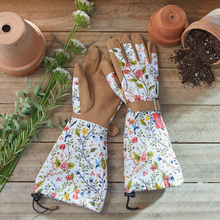 Load image into Gallery viewer, Floral patterned garden gloves with extended arm protection laid flat on wooden surface with terracotta pots