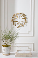 Load image into Gallery viewer, Gold metal bat wreath with spiral wire design displayed on white wall above books and plant