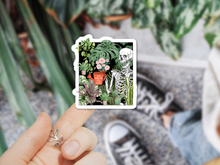 Load image into Gallery viewer, Hand holding skeleton with plants sticker featuring botanical illustration and motivational text