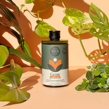 Load image into Gallery viewer, We The Wild Grow Concentrate plant fertilizer bottle surrounded by green houseplants in natural lighting