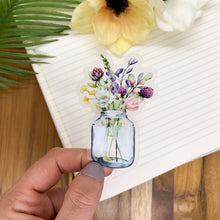 Load image into Gallery viewer, Hand holding watercolor floral mason jar vinyl sticker with wildflowers against white notebook