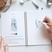 Load image into Gallery viewer, Open spiral-bound watercolor workbook showing apron painting tutorial with step-by-step instructions and hand holding brush