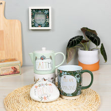 Load image into Gallery viewer, White ceramic garden stone with 'FRIEND' text and floral design on woven placemat