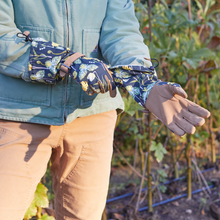 Load image into Gallery viewer, Extended arm protection gardening gloves with floral pattern and brown fingertips being worn outdoors