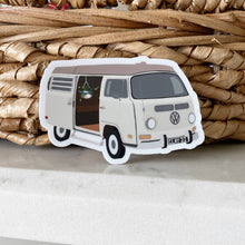 Load image into Gallery viewer, White VW van sticker with open door showing hanging plant, positioned against woven basket background