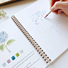 Load image into Gallery viewer, Hand painting watercolor flowers in spiral-bound art workbook with brush and floral exercises