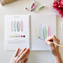 Load image into Gallery viewer, Hands painting watercolor surfboards in tropical colors in spiral-bound art workbook with paint tubes nearby