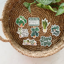 Load image into Gallery viewer, Collection of plant-themed stickers with humorous sayings displayed on woven basket with greenery