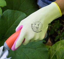 Load image into Gallery viewer, Light green gardening glove with pink fingertips holding pruning shears near plant leaves