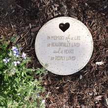 Load image into Gallery viewer, Round memorial garden stone with heart symbol and remembrance text on mulched ground with purple flowers