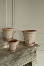 Load image into Gallery viewer, Three terracotta plant pots with decorative arch patterns and matching saucers on stone ledge