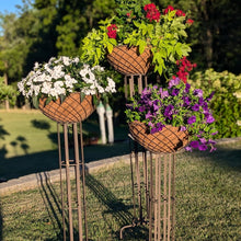 Load image into Gallery viewer, Three metal wire hanging baskets with coconut fiber liners on tall stakes displaying colorful flowers