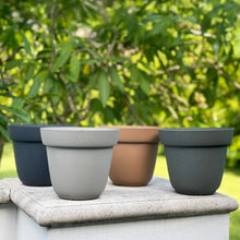 Load image into Gallery viewer, Five colorful ceramic planters in navy, gray, terracotta, and charcoal displayed on stone surface outdoors