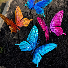 Load image into Gallery viewer, Colorful metal butterfly garden stakes in blue, orange, and pink on dark mulch