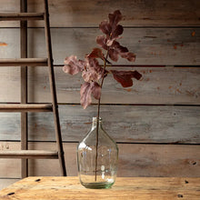 Load image into Gallery viewer, Autumn fig brown branch with burgundy dried leaves displayed in clear glass demijohn vase