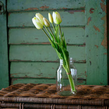 Load image into Gallery viewer, White and green tulip flowers in clear glass jar on wicker basket against weathered green background