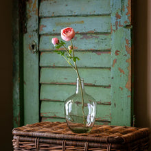 Load image into Gallery viewer, Light pink ranunculus flowers in glass vase against weathered green shutters