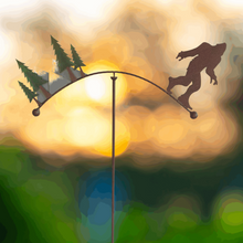 Load image into Gallery viewer, Bigfoot silhouette garden balancer stake with evergreen trees against sunset sky background