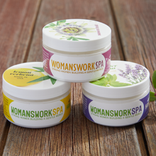 Load image into Gallery viewer, Three WOMANSWORKSPA hand cream jars with floral designs stacked on wooden surface