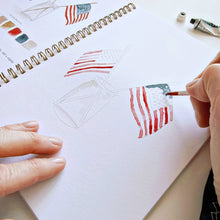 Load image into Gallery viewer, Person painting American flags in watercolor workbook with paint palette and brush