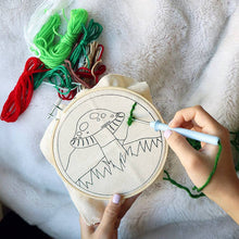 Load image into Gallery viewer, Hands working on mushroom embroidery hoop with colorful thread skeins on white blanket