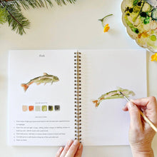 Load image into Gallery viewer, Spiral-bound camping watercolor workbook open to fish painting tutorial with step-by-step instructions